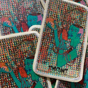 K&ouml;nnte beinhalten: Rechteckiger Aufn&auml;her mit einer t&uuml;rkisfarbenen Figur mit roten und orangen Details, die ein herzf&ouml;rmiges Objekt h&auml;lt. Das Wort "TEMPERANCE" ist wei&szlig; gedruckt. Der Hintergrund ist ein farbenfrohes Muster aus kleinen Formen. Der Aufn&auml;her hat einen wei&szlig;en Rand.