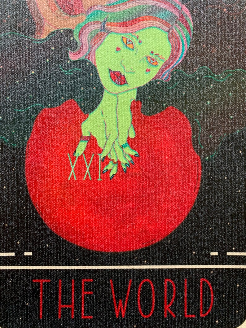 May include: A tarot card illustration of "The World." The card features a green-skinned figure with colorful hair and a red dress, holding a red orb. The card's title and Roman numeral "XXI" are displayed in red on a black background.