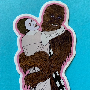 May include: A sticker featuring a cartoon illustration of Princess Leia hugging Chewbacca. Leia is wearing her white outfit from Star Wars. Chewbacca is brown and furry. The sticker has a pink outline.