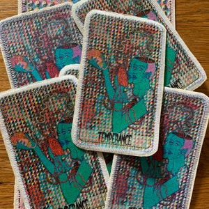 K&ouml;nnte beinhalten: Rechteckige Aufn&auml;her mit einem farbenfrohen, psychedelischen Design mit einer t&uuml;rkisfarbenen Figur mit dem Wort "TEMPERANCE". Die Aufn&auml;her haben einen wei&szlig;en Rand und sind auf einer Holzoberfl&auml;che verstreut.