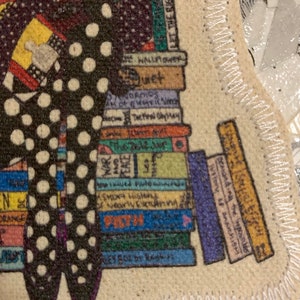 May include: A colourful illustration of a woman sitting on a stack of books. The woman is wearing a black and white polka dot dress and holding a book. The books have titles such as "The Hall Flower", "Normos", "Shoya History", "Demanding the History of anarchISH", and "Peace".