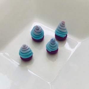 Pode incluir: Quatro pequenos ornamentos de argila feitos &agrave; m&atilde;o, de cor roxa e azul em espiral. Os ornamentos t&ecirc;m a forma de um cone e um padr&atilde;o de espiral de cor azul claro e roxo.