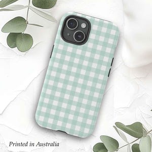 May include: A light green and white checkered phone case with a black camera cutout. The case is designed for a phone with a triple camera lens.