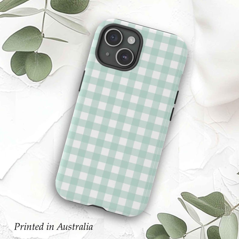 May include: A light green and white checkered phone case with a black camera cutout. The case is designed for a phone with a triple camera lens.
