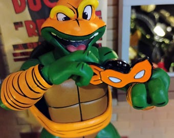 Penguin Random House Exclusive: TMNT 40th Anniversary Comics Celebration—The Deluxe Edition , official 'Michelangelo' banana Enamel pin 2024