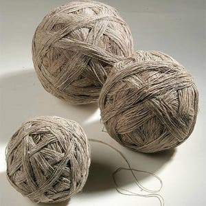 May include: Three balls of natural fiber yarn, each wound in a different size. The yarn is a light brown color and has a rough texture.