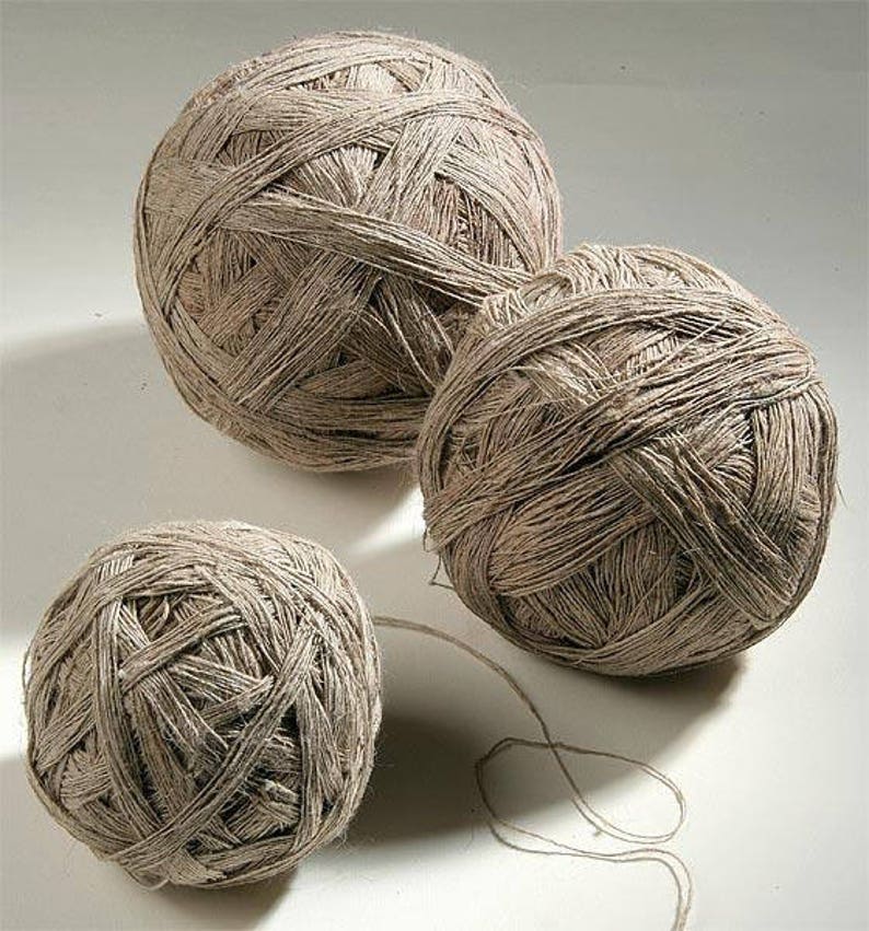 May include: Three balls of natural fiber yarn, each wound in a different size. The yarn is a light brown color and has a rough texture.