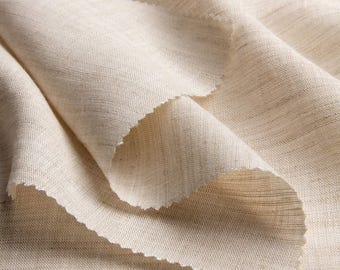 May include: Close-up of a beige fabric with a textured weave. The fabric is folded over itself, creating a soft, draping effect.