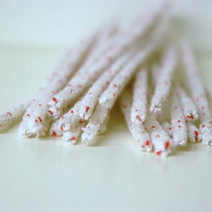 May include: A bunch of white pipe cleaners with red tips. The pipe cleaners are arranged in a loose pile.