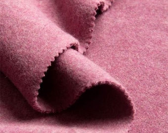 Puede incluir: Primer plano de una tela texturizada rosa empolvado con un borde en bruto y dentado. La tela está doblada y drapeada, mostrando su textura suave y lanosa. El color es un rosa apagado, ideal para ropa o decoración del hogar.