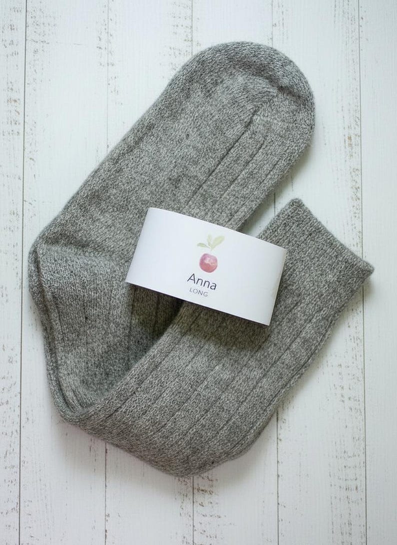 Brown unfolded long Anna wool sock with a white label on a white wooden rustic background