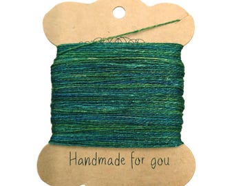 May include: A spool of green and blue yarn with a brown paper label that says "Handmade for you".