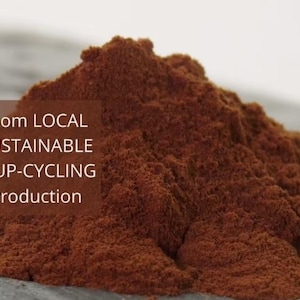 Könnte beinhalten: Nahaufnahme eines Haufens dunkelbraunen Pulvers. Der Text "From LOCAL SUSTAINABLE & UP-CYCLING Production" ist im Bild sichtbar.