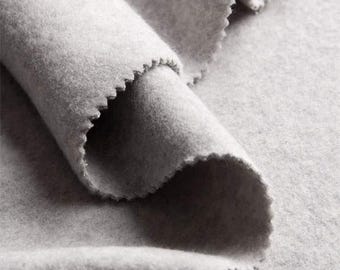 May include: Close-up of a soft, gray fabric with a fuzzy texture. The fabric is folded and draped, showing its drape and texture.