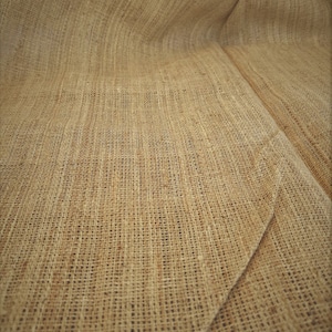 May include: Close-up of a brown burlap fabric with a woven texture. The fabric is folded and has a natural, rustic look.