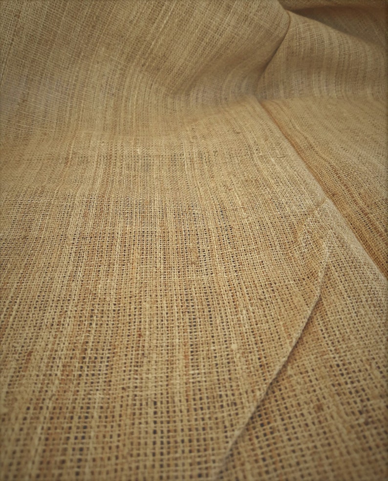 May include: Close-up of a brown burlap fabric with a woven texture. The fabric is folded and has a natural, rustic look.
