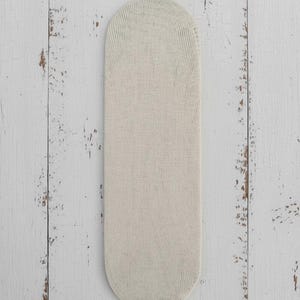 Rosa no show white sock stretched upside down over cardboard on a white wooden floor