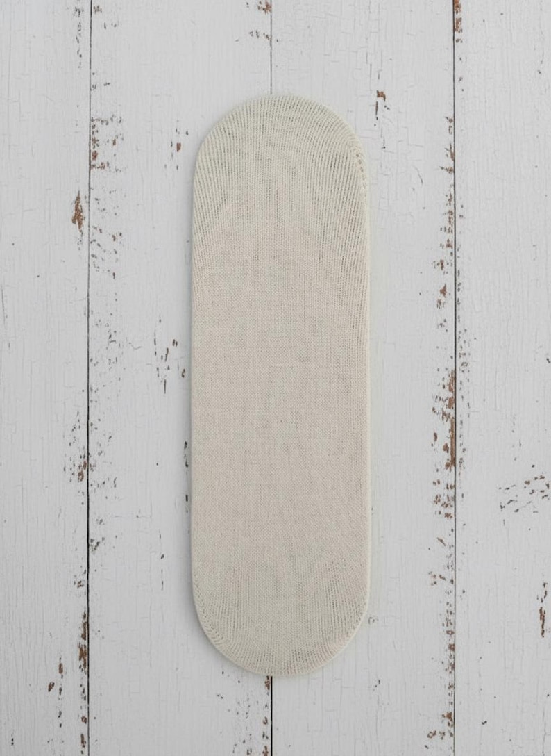 Rosa no show white sock stretched upside down over cardboard on a white wooden floor