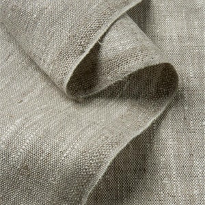 Puede incluir: Primer plano de una tela de lino natural con un tejido texturizado. La tela es de color beige claro y tiene un tacto ligeramente áspero.
