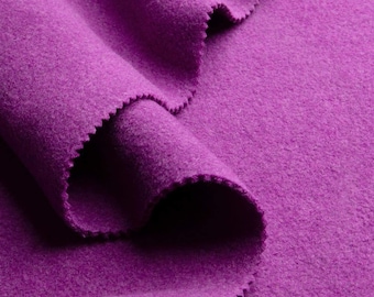 Puede incluir: Primer plano de una vibrante tela morada con un aspecto suave y texturizado. Los bordes de la tela están cortados con un patrón en zigzag. El material está doblado, creando sombras y resaltando la profundidad del color.