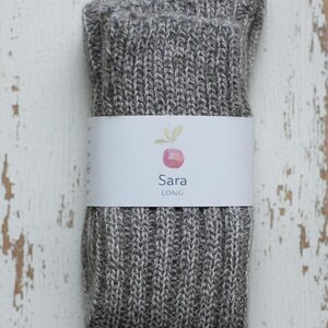 Grey knitted socks with a white label on a rustic wooden surface