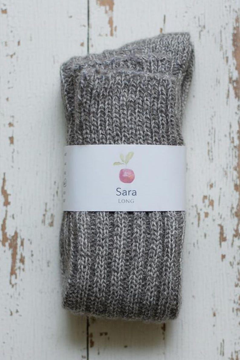 Grey knitted socks with a white label on a rustic wooden surface