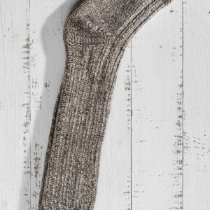 brown long knitted wool sock on a rustic wooden surface
