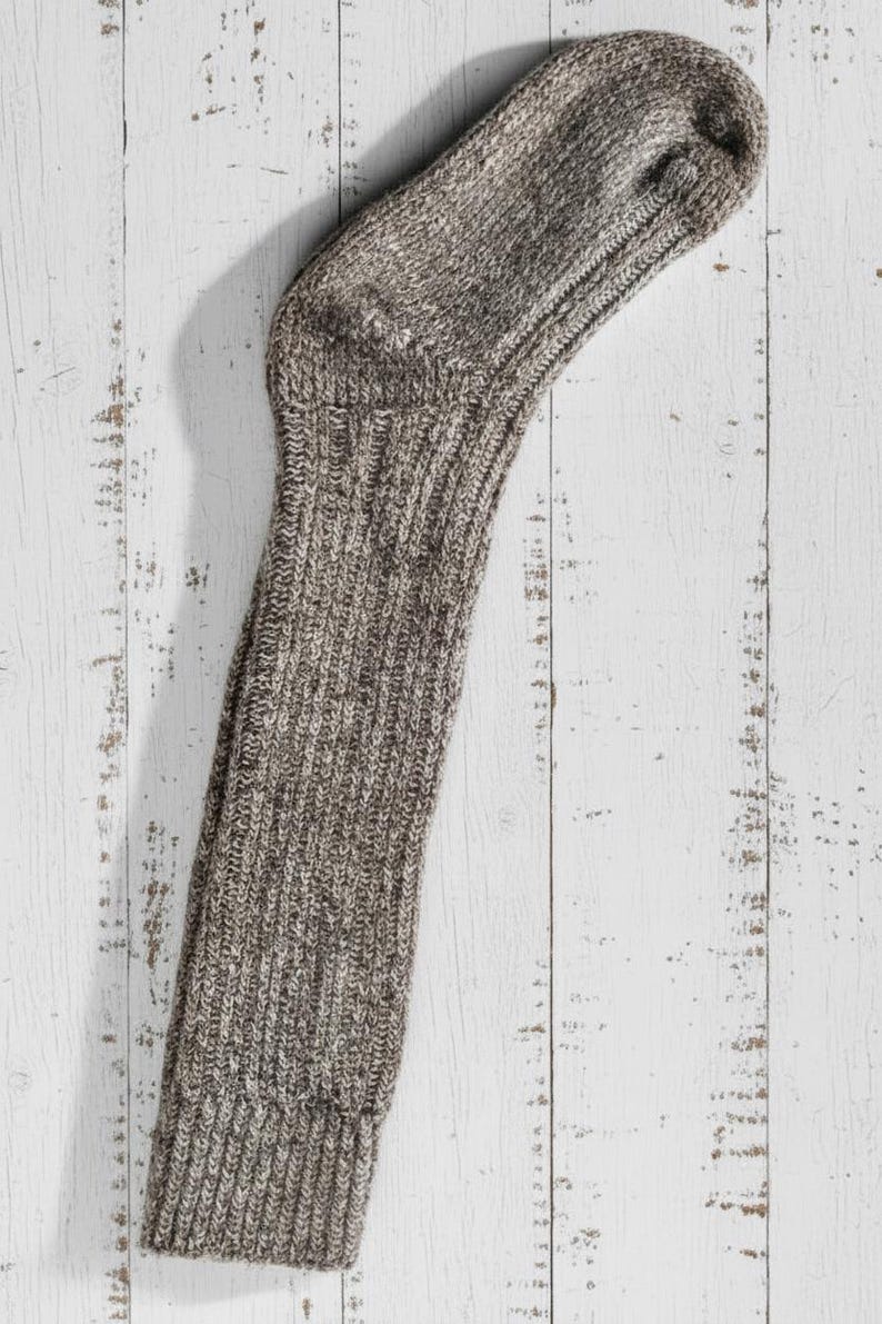 brown long knitted wool sock on a rustic wooden surface