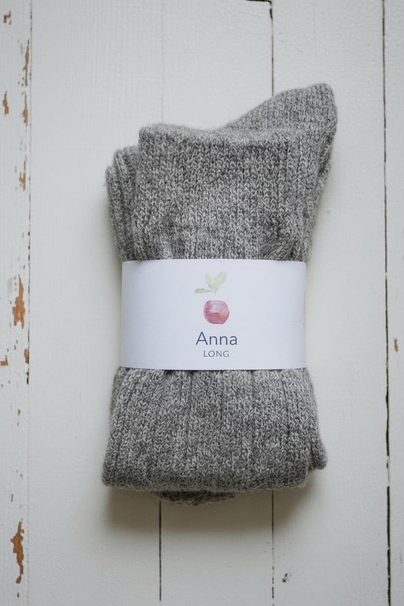 Brown double folded long Anna wool sock with a white label on a white wooden rustic background