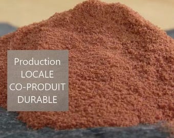 May include: Close-up of a pile of reddish-brown powder. Text on the left side of the image reads: "Production Locale Co-Produit Durable".