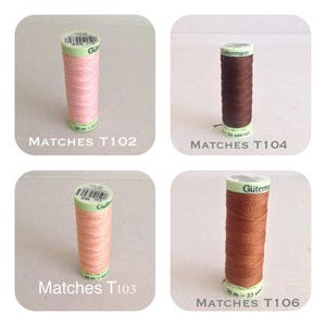 May include: Four spools of thread, each in a different colour: pink, brown, peach, and orange. The spools are labelled with the brand name "Gütermann" and the product code "T102", "T104", "T103", and "T106".