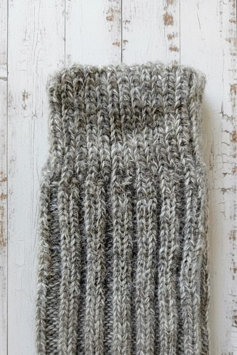 Wool sock cuff in grey brown on a white wooden surface.
