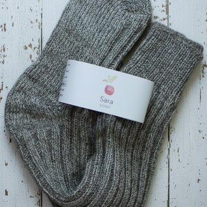 Unfolded Grey knitted sock with a white label on a rustic wooden surface