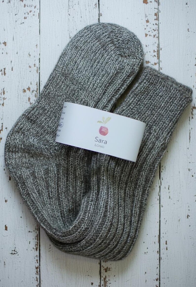 Unfolded Grey knitted sock with a white label on a rustic wooden surface