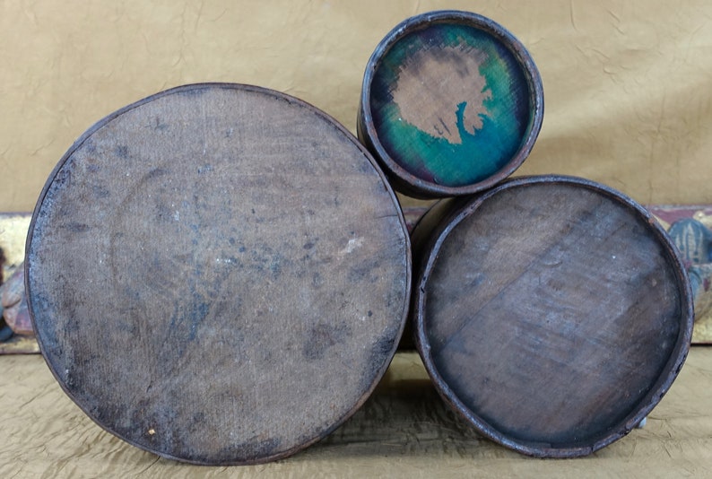May include: Three wooden nesting boxes with lids. The largest box is brown and has a smooth surface. The middle box is brown and has a smooth surface. The smallest box is brown with a blue and green painted interior.