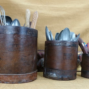 May include: Four brown wooden containers with metal bands and lids, used for storing kitchen utensils. The containers are labeled "One Litre" and "Double Litre".