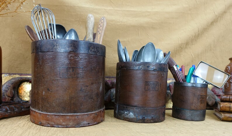 May include: Four brown wooden containers with metal bands and lids, used for storing kitchen utensils. The containers are labeled "One Litre" and "Double Litre".