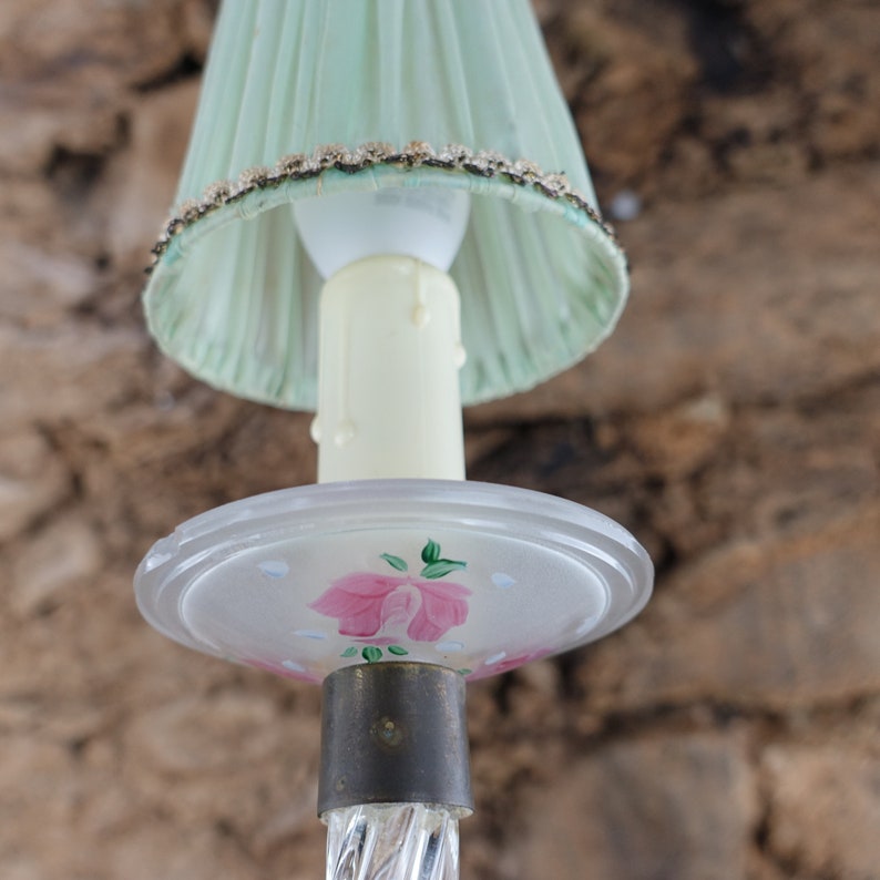 May include: A vintage lamp with a green fabric shade and a frosted glass base with a painted pink rose design.