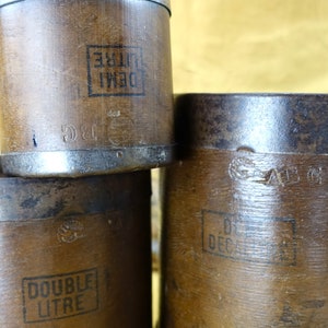 May include: Four wooden containers with metal bands and markings. The containers are labeled "DEMI LITRE", "DOUBLE LITRE", "DECI LITRE", and "ABG".