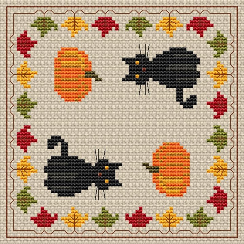 May include: Cross-stitch design with two black cats and two orange pumpkins. The design is framed by a border of autumn leaves in red, yellow, and green. The background is a light beige colour.
