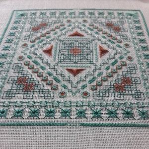 Könnte beinhalten: Ein quadratisches Kreuzstichmuster mit einem geometrischen Design in Grün- und Brauntönen. Die Mitte des Musters zeigt ein Quadrat mit einem kleineren Quadrat im Inneren, umgeben von einer Reihe von Dreiecken und Rauten.