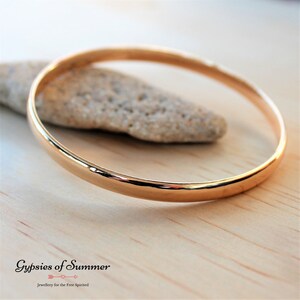 May include: A simple gold bangle bracelet, a classic piece of jewelry.