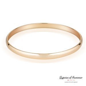 May include: A simple gold bangle bracelet. The bracelet is smooth and has a polished finish.