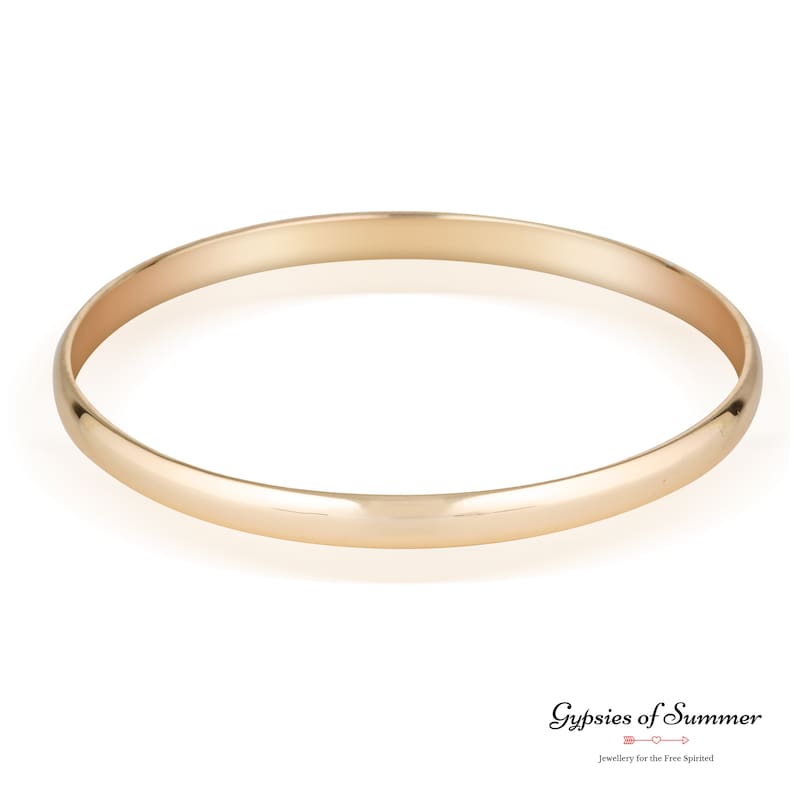 May include: A simple gold bangle bracelet. The bracelet is smooth and has a polished finish.