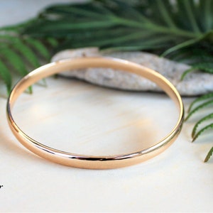 May include: A simple gold bangle bracelet, a classic piece of jewelry.