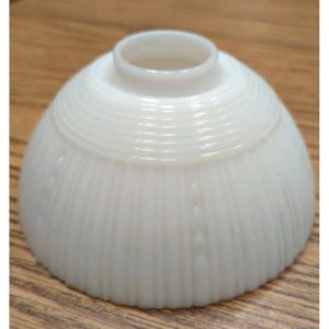 May include: A white, dome-shaped glass lampshade with a ribbed texture. The lampshade has a small, cylindrical opening at the top and a rounded base. The surface has vertical grooves and a subtle, textured pattern.