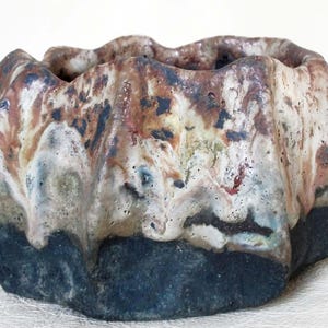 May include: A small, ceramic planter with a textured, wavy surface. The planter is decorated with brown, white and black glaze.