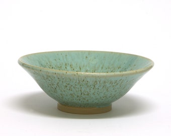 Ceramic bowl with a different appearance in turquoise shade, scattered with dark and elongated spots. A handmade gift.