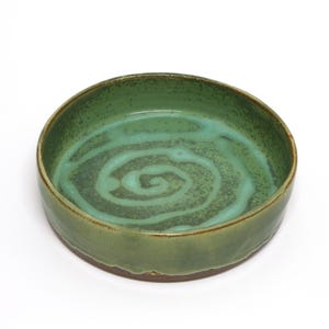 May include: A green ceramic bowl with a swirling pattern in the glaze.