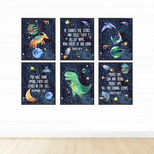 May include: Six printable wall art prints featuring dinosaurs in space with inspirational bible verses. The prints have a dark blue background with stars, planets, and comets. The dinosaurs are green, orange, and blue. The verses are: "He counts the stars and calls them all by name. How great is our Lord! Psalm 147:4", "You will shine among them-like stars in the sky. Philippians 2:15", "Praise Him, sun and moon: Praise Him all you shining stars. Psalm 148:3"